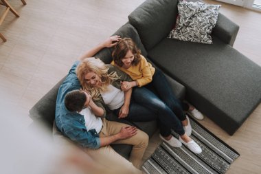 Genç adam güzel karısı ve kızı ile kanepede oturan