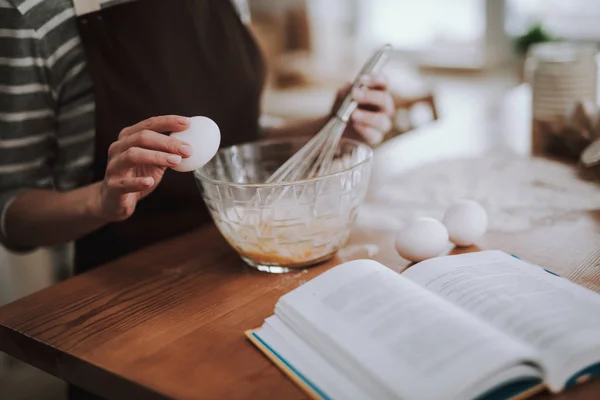Mulher está batendo ovos na cozinha em casa — Fotografia de Stock