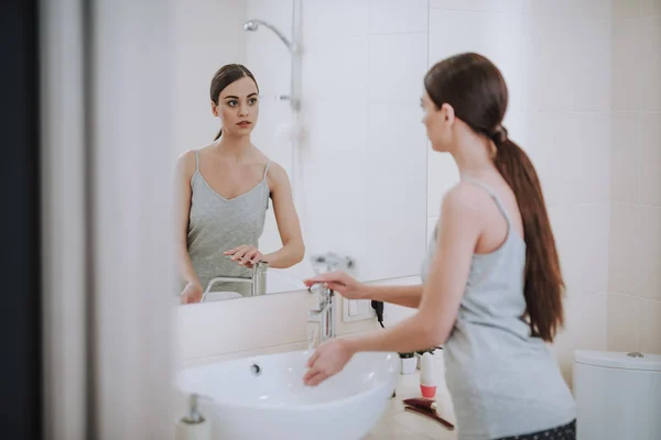Beautiful young woman looking in the mirror — Stock Photo, Image