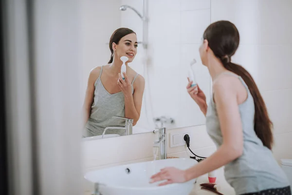 Positive nice woman suing her face massager — Stock Photo, Image