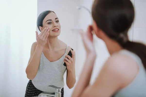 Attractive smiling woman using her face gel — Stock Photo, Image