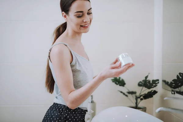 Banyoda bir krem kavanoz tutan neşeli kadın — Stok fotoğraf