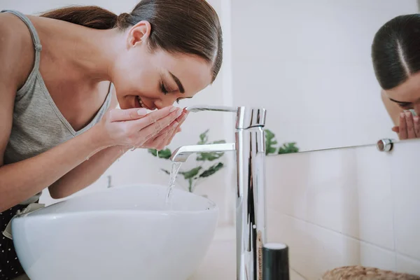 Hoş gülümseyen genç kadın sabah yüzünü yıkama — Stok fotoğraf
