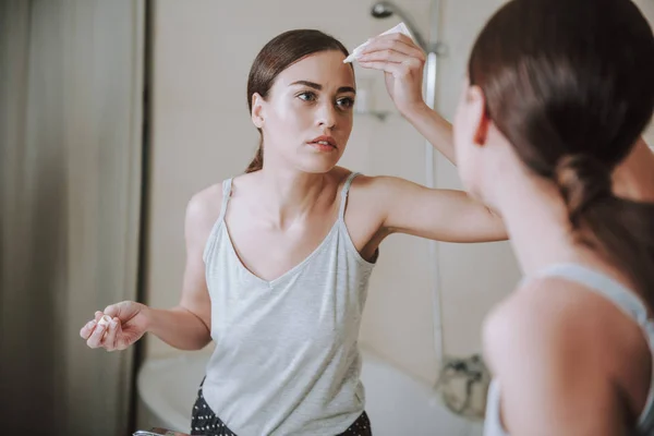 Wanita serius baik menerapkan gel wajah di depan cermin — Stok Foto