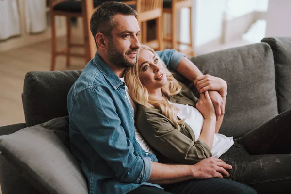 Knappe bebaarde man knuffelen zijn charmante vrouw terwijl ze zijn hand vasthoudt — Stockfoto