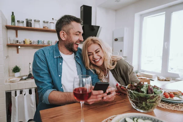 Glatt lyckligt par med hjälp av smartphones och äta middag hemma — Stockfoto