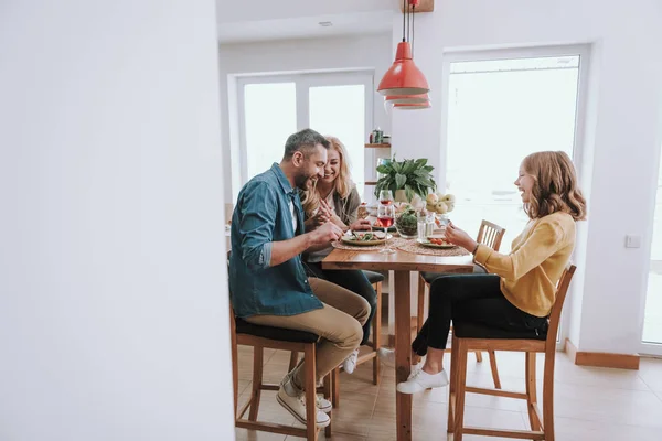 Lycklig familj som har middag, chattar och skrattar hemma — Stockfoto