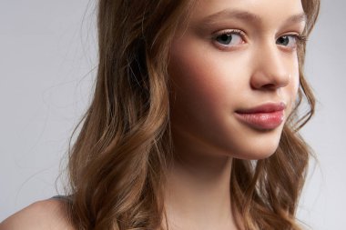 Gri-beyaz arka plan aleyhine duran mükemmel bir cilt ile Charming genç kız