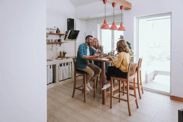 Família feliz conversando e rindo enquanto janta em casa — Fotografia de Stock