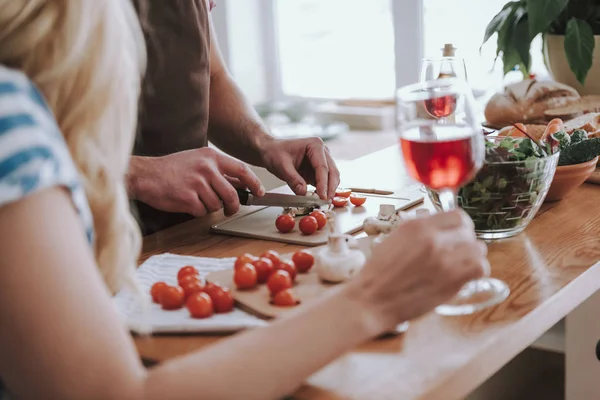 Man koken diner terwijl zijn dame het houden van glas wijn — Stockfoto