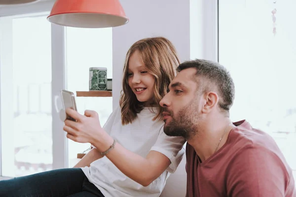 Adorabile bambina e suo padre guardando video divertenti su smartphone — Foto Stock