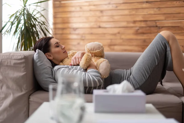 Bruna donna caucasica sdraiata sul divano con giocattolo in braccio — Foto Stock