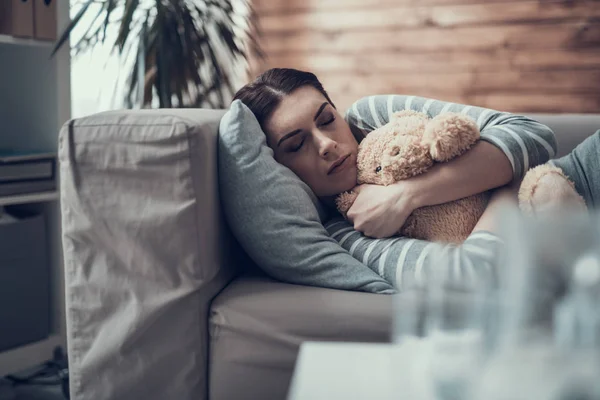 Bruna caucasica donna assonnata sdraiata sul divano con giocattolo in braccio — Foto Stock