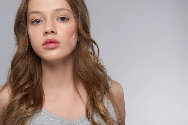 Schöne Teenie-Mädchen mit langen braunen Haaren posiert vor grau-weißem Hintergrund — Stockfoto