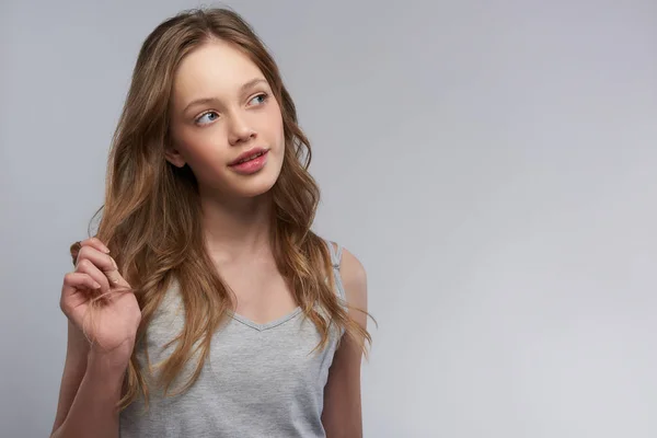 Charming teen girl in tank top standing against gray-white background — Stock Photo, Image