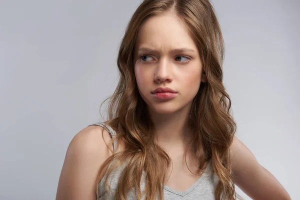 Upset teen girl standing against gray-white background — Stock Photo, Image