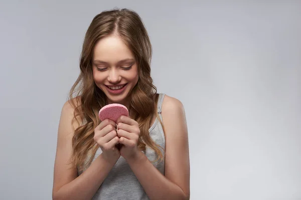 Niedliches Teenie-Mädchen schaut auf rosa Schwamm und lächelt — Stockfoto