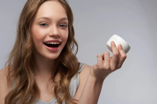 Glad tonårs flicka med perfekt hud visar kosmetisk produkt — Stockfoto