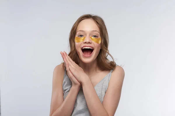 Gelukkig tiener meisje met behulp van gouden onder-oog patches — Stockfoto