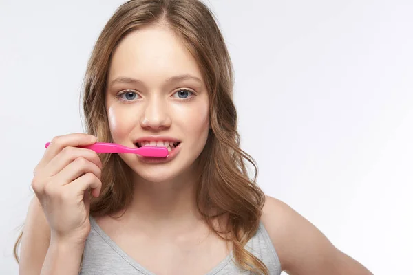 Vacker tonårs flicka borsta tänderna samtidigt stående mot vit bakgrund — Stockfoto