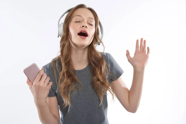 Mooie tiener meisje in draadloze koptelefoon genieten van favoriete liedjes op mobiele telefoon — Stockfoto