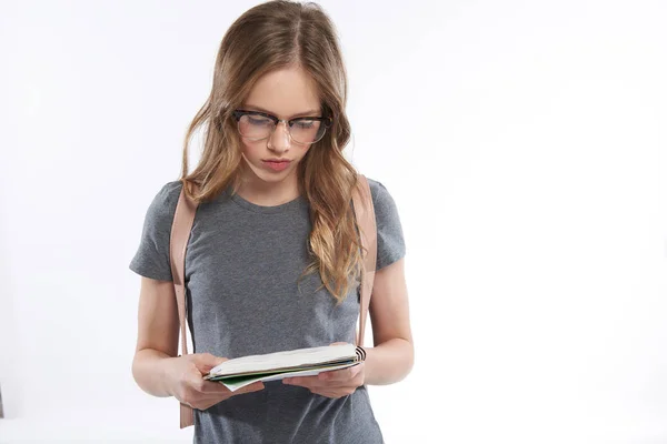 Gyönyörű tini lány szemüveg nézi spirál notebook — Stock Fotó