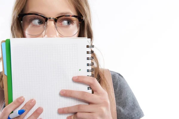 Menina adolescente bonito segurando caneta e rosto de cobertura com caderno espiral — Fotografia de Stock