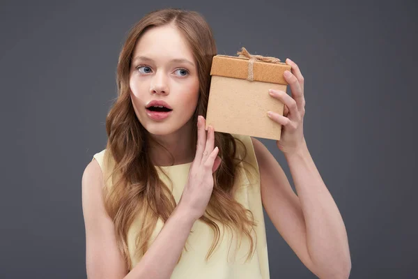 美丽的青少年女孩拿着礼物盒靠近她的耳朵 — 图库照片
