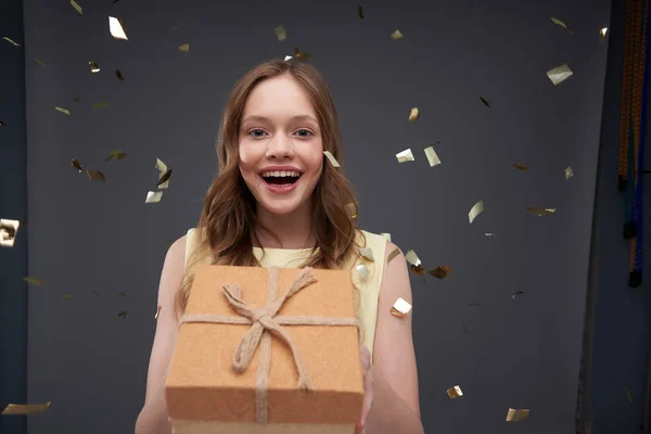 Весела дівчина-підліток з довгим коричневим волоссям тримає подарункову коробку — стокове фото