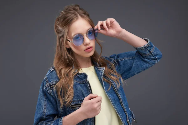 블루 그레이 배경에 대해 포즈를 취하는 청바지 재킷의 매력적인 십대 소녀 — 스톡 사진
