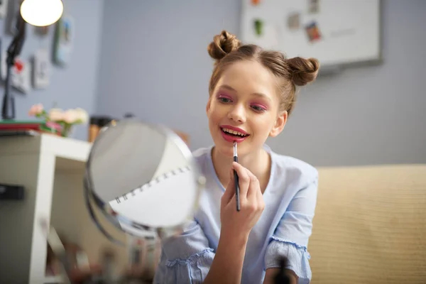 Charmantes Teenie-Mädchen trägt roten Lippenstift mit Pinsel auf — Stockfoto