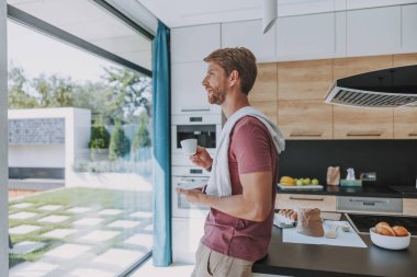 Penceresinden bir manzaranın tadını çıkaran genç adam