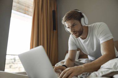 Yatakta bir online oyun oynayan konsantre adam