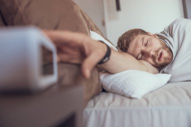 Çalar saatini kapatmaya çalışan adam