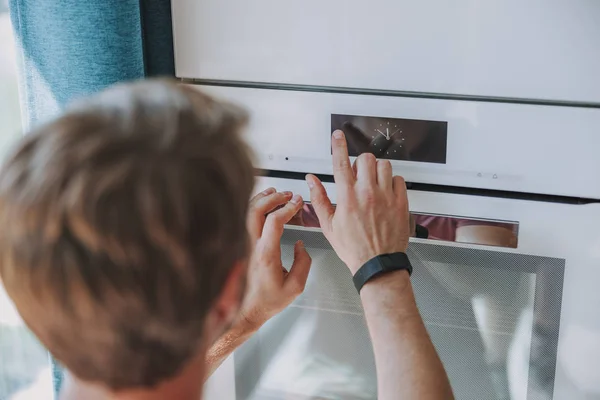 Man sätter sin bakverk i ugnen — Stockfoto