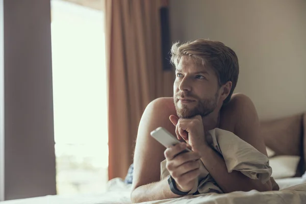 Hombre guapo viendo la televisión después de despertar —  Fotos de Stock