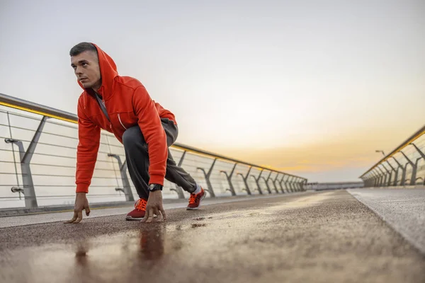 Concentrated male athlete standing on a bridge — Stock Photo, Image