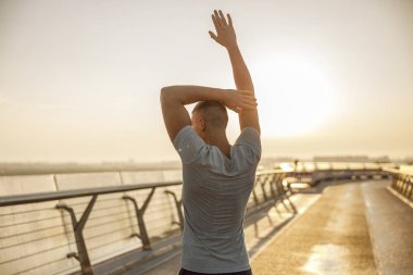 Atlet bir yaya köprüsü üzerinde kollarını germe