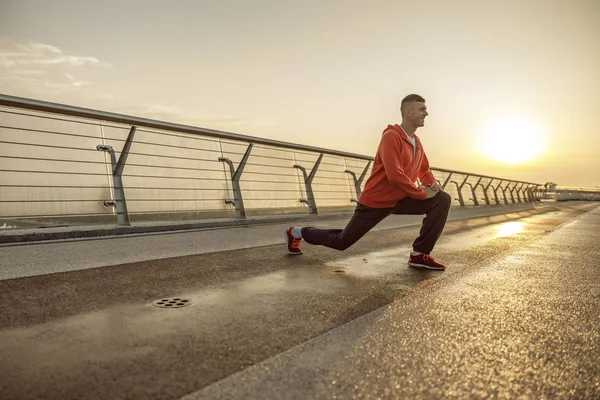 Χαμογελαστός αθλητής που τεντώνει τα πόδια σε μια γέφυρα — Φωτογραφία Αρχείου