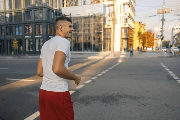 Εύθυμος νεαρός άνθρωπος διασχίζοντας το δρόμο στο κέντρο της πόλης — Φωτογραφία Αρχείου