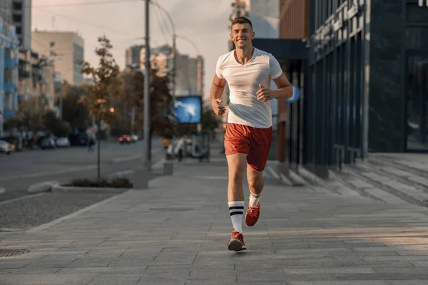 Ευχαριστημένος νέος αθλητής τρέχει κατά μήκος του δρόμου — Φωτογραφία Αρχείου