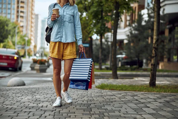 Woman with shopping bags and coffee to go stock photo — Stock Photo, Image
