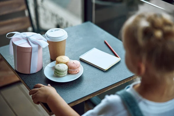 Дівчина сидить за столом з печивом і ноутбуком фото — стокове фото