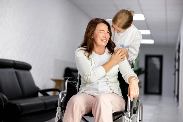 Doctor ayudando a dama alegre en silla de ruedas foto de stock — Foto de Stock