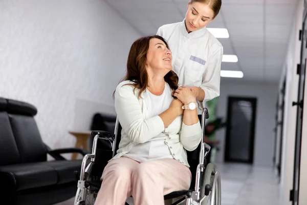 Дружелюбная медсестра помогает женщине с ограниченными возможностями фото — стоковое фото