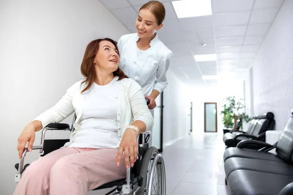 Mujer alegre moviéndose en silla de ruedas en la clínica foto de stock — Foto de Stock