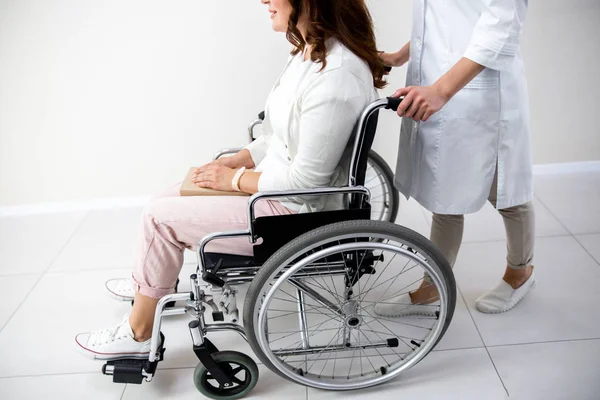 Femme en fauteuil roulant se déplaçant avec infirmière aide photo stock — Photo