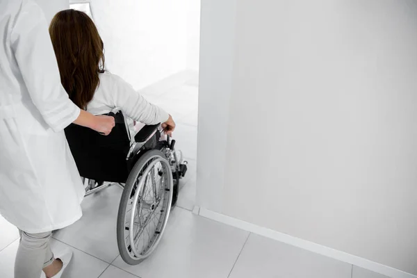 Enfermera ayudando a paciente femenino en silla de ruedas — Foto de Stock