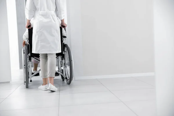Врач перевозит пациента на инвалидной коляске — стоковое фото