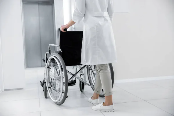 Médecin se déplaçant avec fauteuil roulant vide à l'ascenseur — Photo